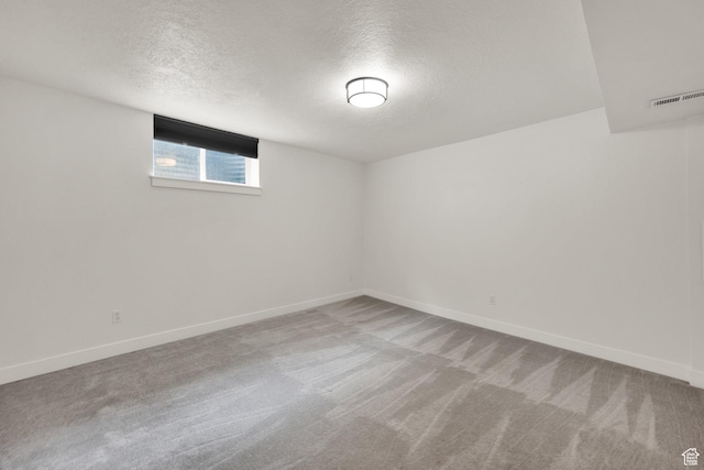 spare room with a textured ceiling, carpet flooring, and baseboards