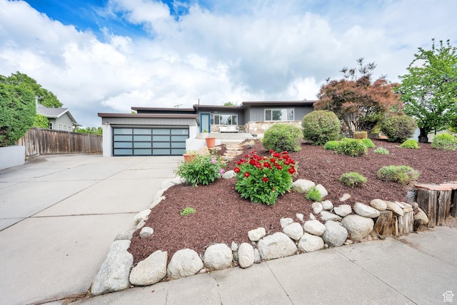 view of front of house featuring a garage, driveway, fence, and stucco siding