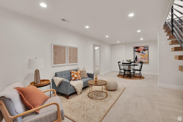 living room with recessed lighting, light colored carpet, baseboards, and stairs