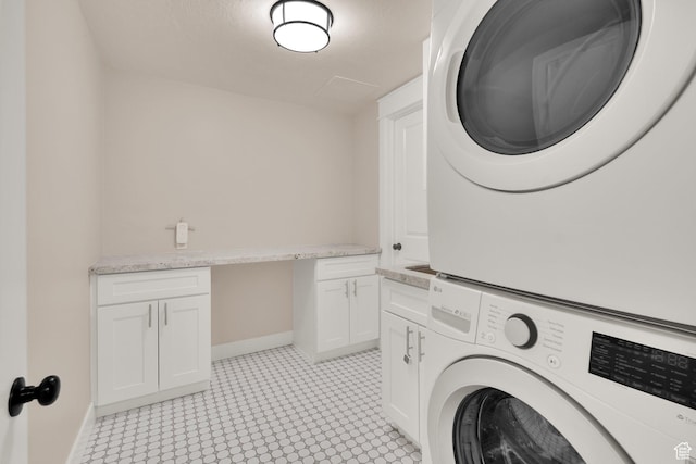 laundry room featuring stacked washer and clothes dryer, cabinet space, baseboards, and light flooring