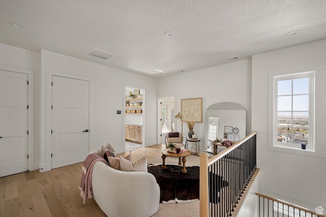 1565 N Overolook Ct, Farmington, UT 84025 - living area with light wood-type flooring, a textured ceiling, arched walkways, and baseboards