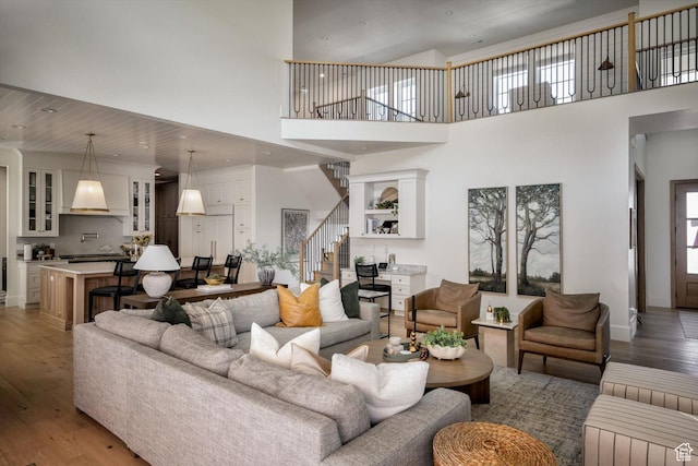1565 N Overolook Ct, Farmington, UT 84025 - living area featuring stairs, light wood-type flooring, a towering ceiling, and baseboards