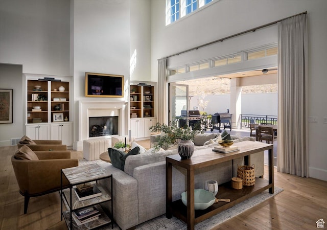 1565 N Overolook Ct, Farmington, UT 84025 - living room with a fireplace with raised hearth, a towering ceiling, built in features, wood finished floors, and baseboards