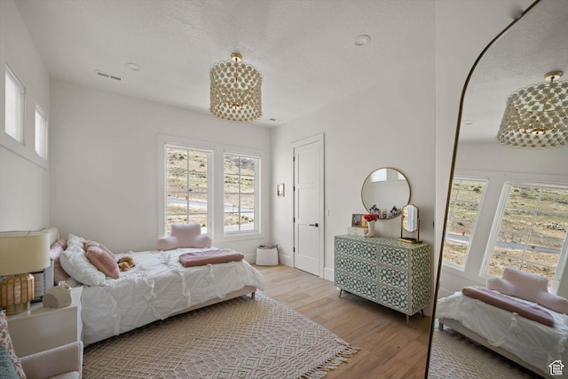 1565 N Overolook Ct, Farmington, UT 84025 - bedroom featuring wood finished floors, a chandelier, and a textured ceiling