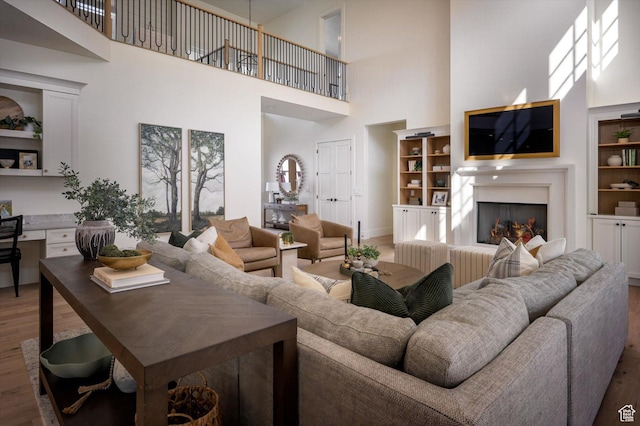1565 N Overolook Ct, Farmington, UT 84025 - living area featuring wood finished floors, a high ceiling, a lit fireplace, and baseboards