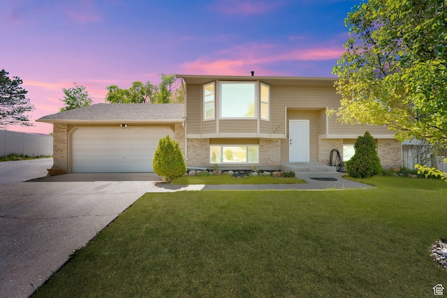 4242 S 6530 W, West Valley City, UT 84128 - bi-level home with brick siding, concrete driveway, an attached garage, and a front lawn