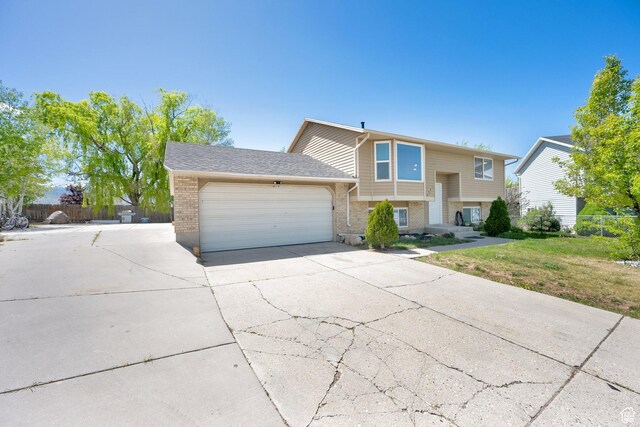 4242 S 6530 W, West Valley City, UT 84128 - bi-level home featuring an attached garage, driveway, fence, and brick siding