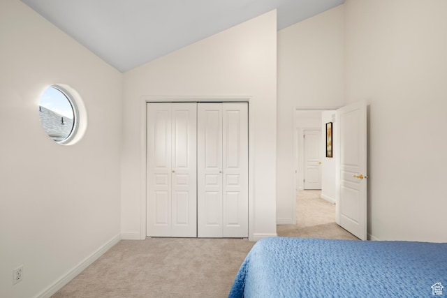 bedroom featuring light colored carpet, high vaulted ceiling, baseboards, and a closet