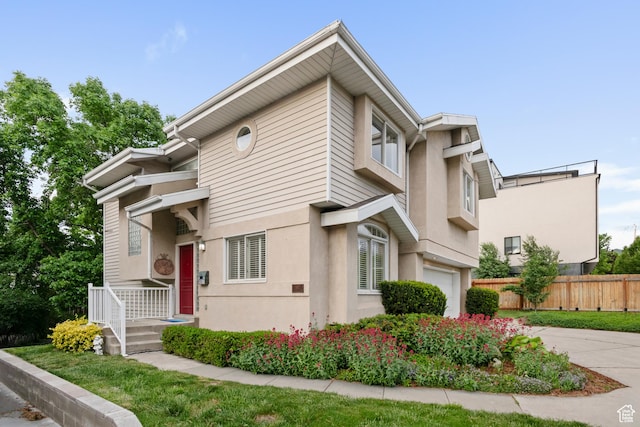 townhome / multi-family property with an attached garage, fence, stucco siding, and driveway
