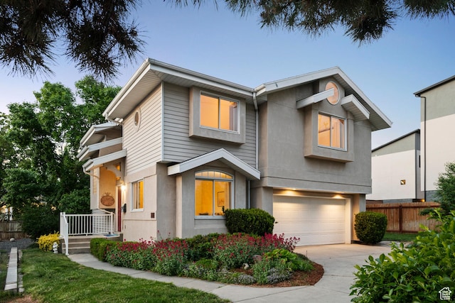 view of front facade with fence, a garage, driveway, and stucco siding