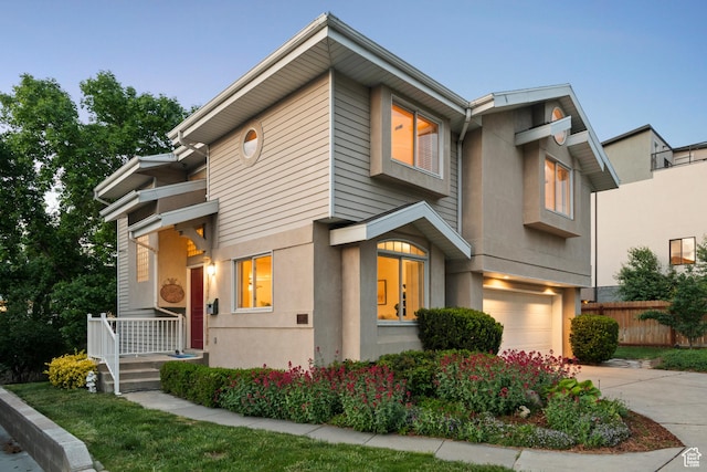 view of front of home featuring a garage, concrete driveway, stucco siding, and fence