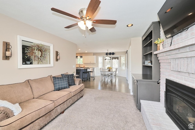 living room with a ceiling fan, a fireplace, recessed lighting, and light wood-style floors