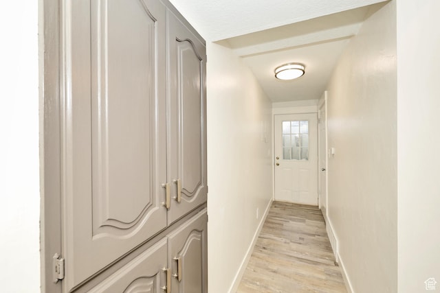 corridor featuring baseboards and light wood-style flooring