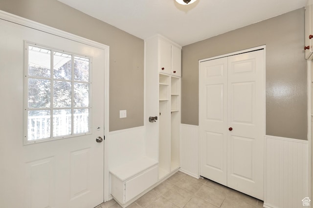 doorway to outside with a wainscoted wall, healthy amount of natural light, and light tile patterned flooring