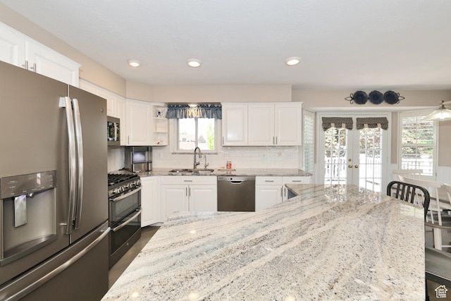 kitchen with appliances with stainless steel finishes, a sink, french doors, white cabinetry, and recessed lighting