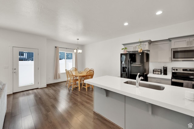 kitchen with appliances with stainless steel finishes, gray cabinets, a sink, light countertops, and recessed lighting