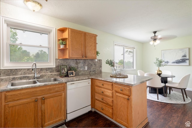 kitchen featuring white dishwasher, a sink, a peninsula, dark wood finished floors, and tasteful backsplash