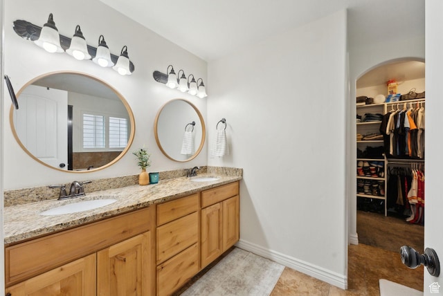 full bath featuring double vanity, a spacious closet, and baseboards