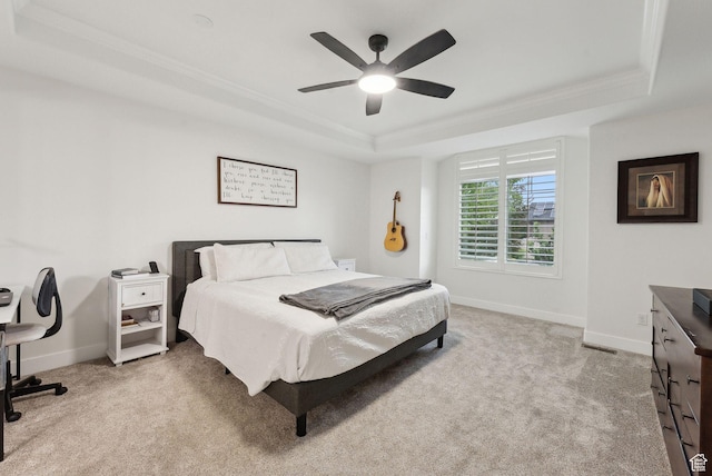 bedroom with a raised ceiling, light carpet, crown molding, baseboards, and a ceiling fan