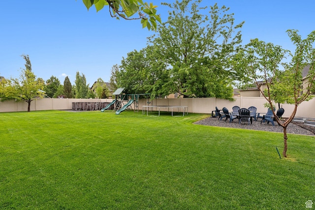 view of yard with a playground, a trampoline, and an outdoor fire pit