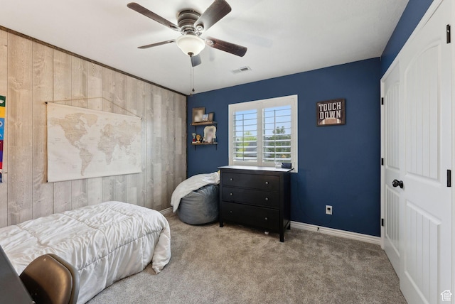 carpeted bedroom with wood walls, ceiling fan, and baseboards