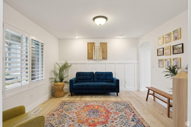 sitting room featuring arched walkways and wood finished floors