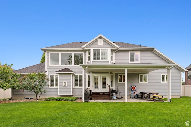 rear view of property with roof with shingles, a yard, and a patio area