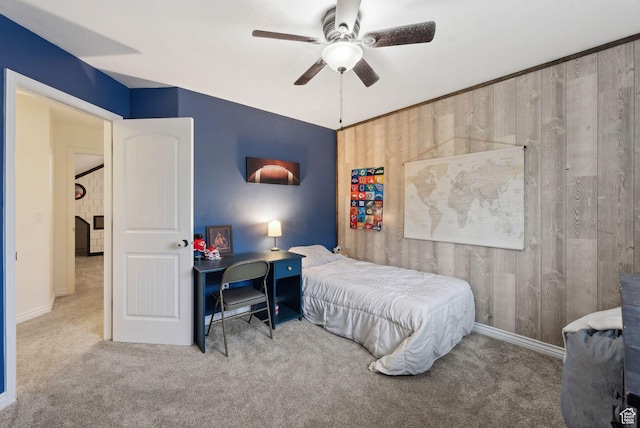 bedroom with wood walls, carpet flooring, baseboards, and ceiling fan