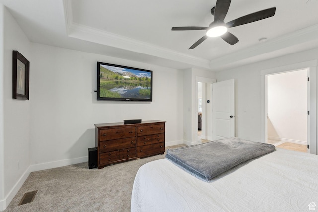 bedroom featuring a tray ceiling, ornamental molding, light colored carpet, ceiling fan, and baseboards