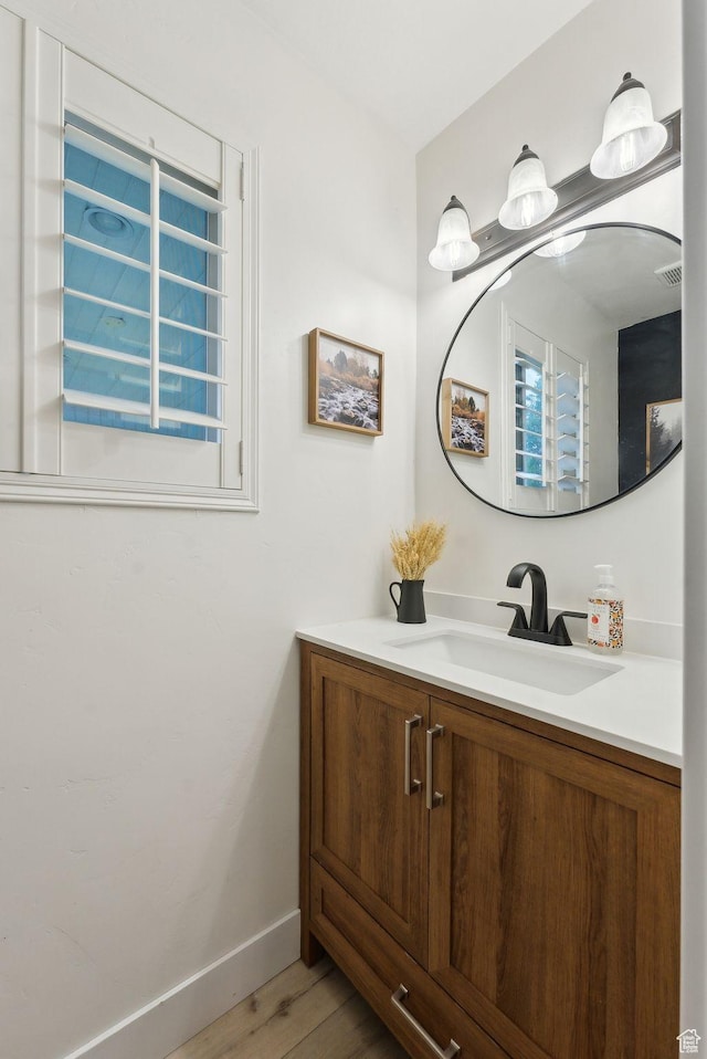 bathroom with vanity, wood finished floors, and baseboards