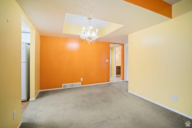unfurnished room with a chandelier, carpet flooring, baseboards, and a textured ceiling