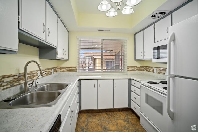 kitchen with white appliances, a sink, a chandelier, light countertops, and white cabinets