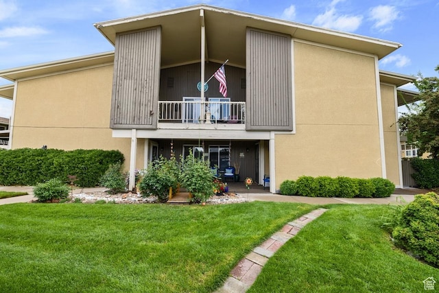 rear view of property featuring a balcony and a yard