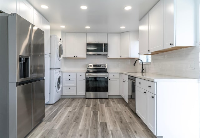 4740 S 3040 W, Taylorsville, UT 84129 - kitchen featuring appliances with stainless steel finishes, stacked washer / dryer, a sink, light countertops, and white cabinetry