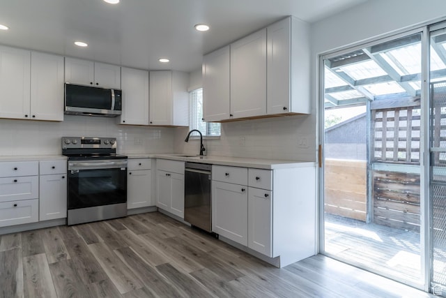 4740 S 3040 W, Taylorsville, UT 84129 - kitchen with stainless steel appliances, light countertops, decorative backsplash, light wood finished floors, and white cabinetry