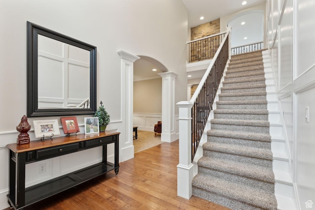 1737 S Kerrybrook Dr, Kaysville, UT 84037 - stairs featuring decorative columns, arched walkways, wood finished floors, a decorative wall, and recessed lighting
