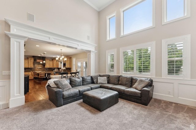 1737 S Kerrybrook Dr, Kaysville, UT 84037 - carpeted living area featuring ornate columns, a chandelier, a high ceiling, a wainscoted wall, and a decorative wall