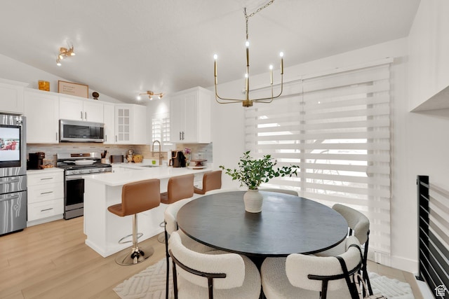 dining space featuring vaulted ceiling and light wood-style floors