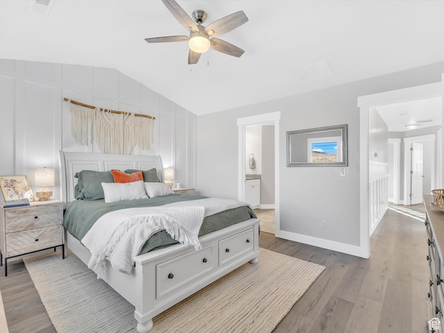 bedroom featuring vaulted ceiling, light wood-type flooring, baseboards, ceiling fan, and ensuite bathroom