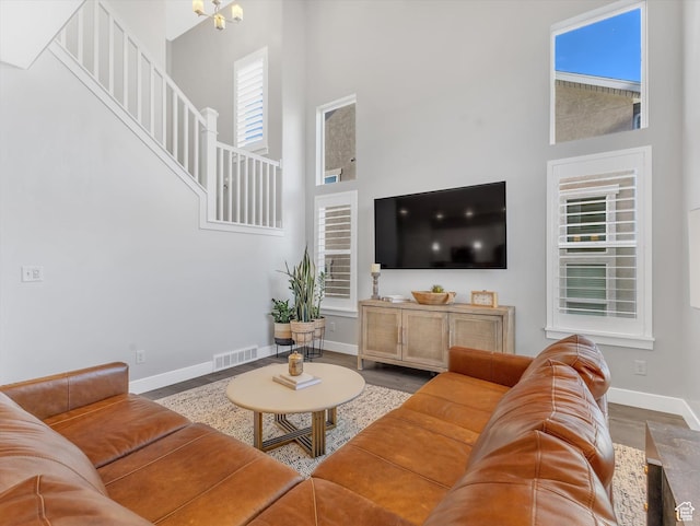 living area featuring a high ceiling, baseboards, wood finished floors, and stairs