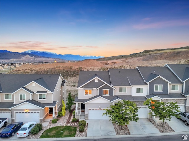 townhome / multi-family property featuring driveway, board and batten siding, a mountain view, a garage, and a residential view