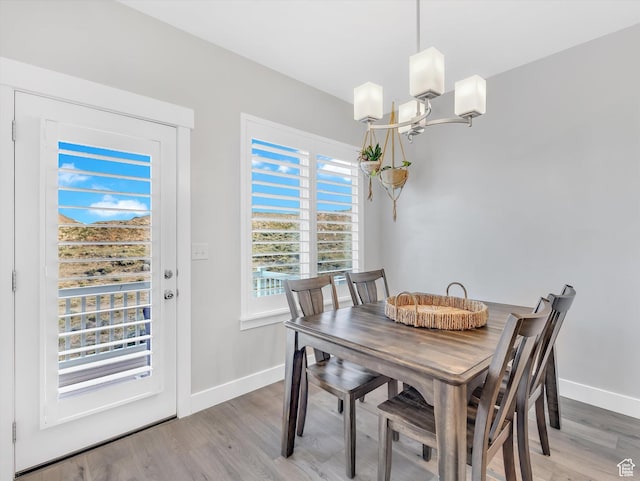 dining space featuring a chandelier, light wood-style flooring, and baseboards