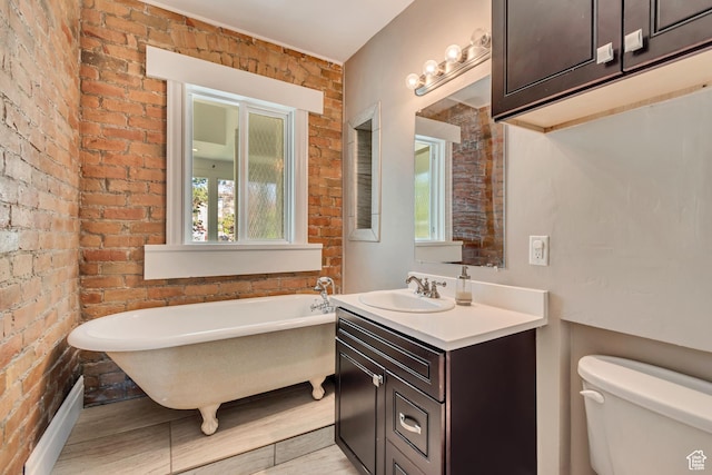215 E 2nd Ave S, Salt Lake City, UT 84103 - bathroom with toilet, a soaking tub, vanity, brick wall, and wood finished floors