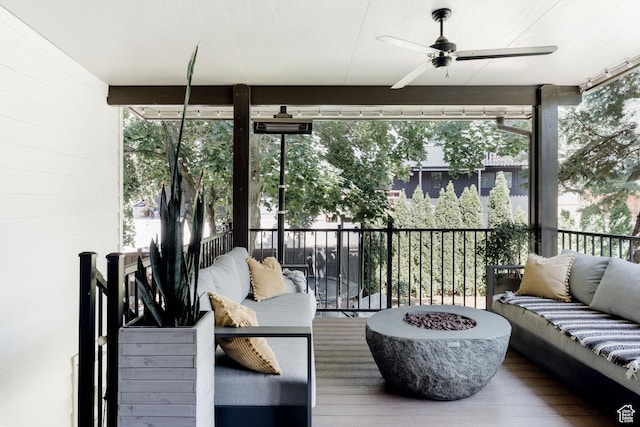 sunroom featuring an outdoor living space with a fire pit, a ceiling fan, and plenty of natural light