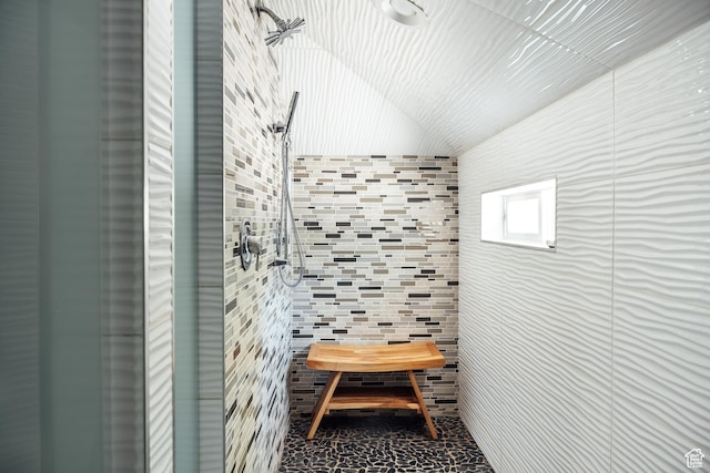 full bath featuring tile walls, a tile shower, and vaulted ceiling