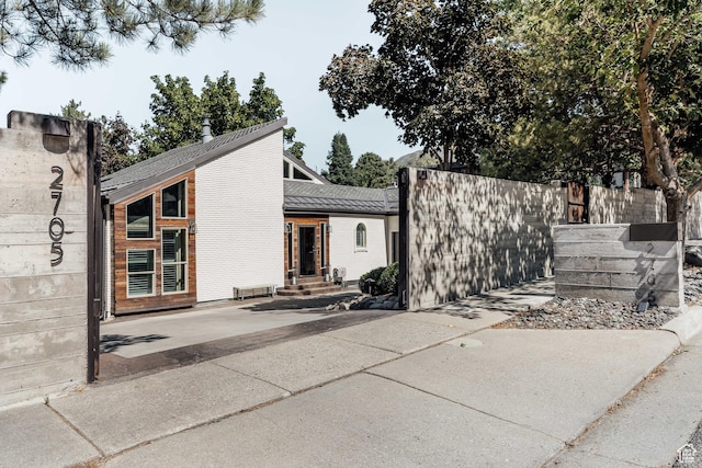 rear view of house with entry steps, fence, and a shingled roof