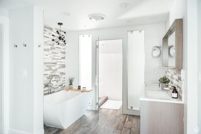 full bath with backsplash, a soaking tub, wood finished floors, walk in shower, and recessed lighting