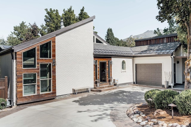 view of front of home with a garage, driveway, a standing seam roof, a mountain view, and metal roof