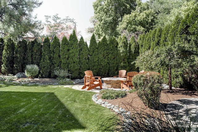 view of grassy yard featuring an outdoor fire pit and a patio