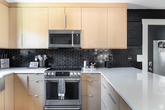 kitchen featuring appliances with stainless steel finishes, light brown cabinetry, light countertops, backsplash, and modern cabinets